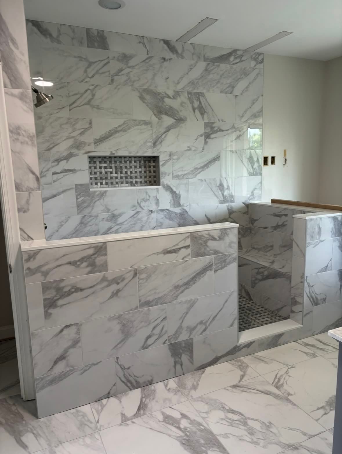 Walk-in marble shower with built-in seat, niche, and tile threshold