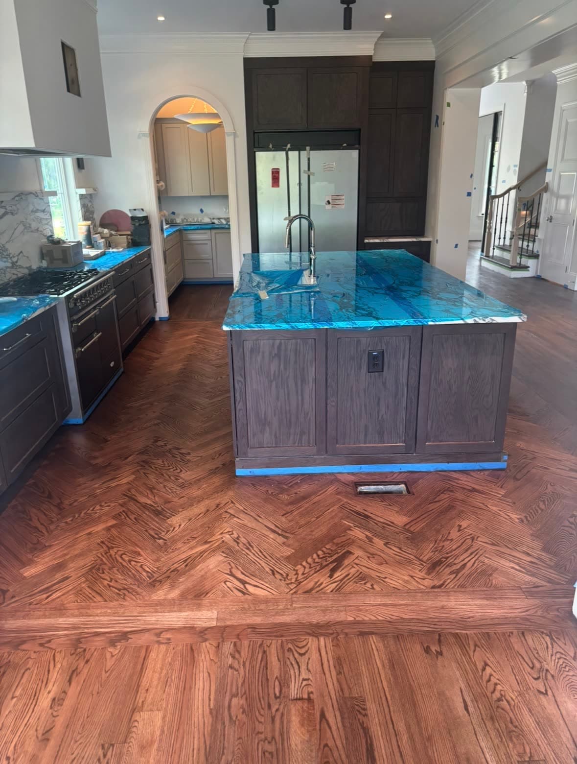 Herringbone red oak hardwood floor with dark perimeter border in a custom kitchen with blue agate island